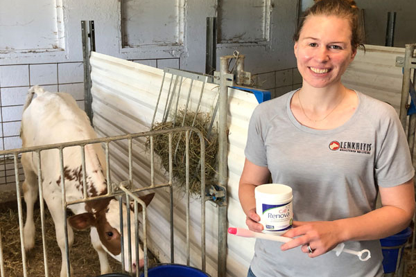 Photo of Sarah Lenkaitis of Lankaitis Farms in Illinois pictured with a bottle of Calf Renova and applicator with a calf in a pen behind her